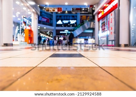 In the mall. Multi-colored illuminated signs. Glass shop windows. Product selection. Go shopping. Focus on the floor. Close up view from the level of the floor tiles.