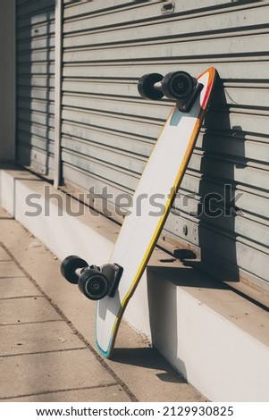 The surfskate leaning against rolling steel door. Extreme sport equipment.