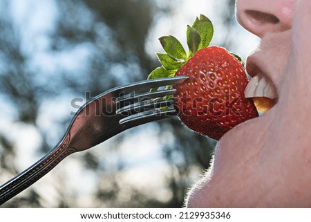A woman bitting in a strawberry