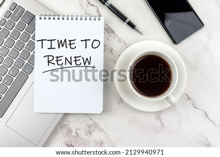 Time to renew phrase on notepad with cup of coffee and laptop