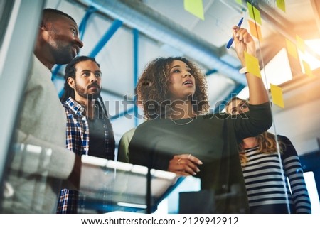 Sharing experience and expertise for an excellent brainstorming session. Shot of colleagues having a brainstorming session with sticky notes at work. Royalty-Free Stock Photo #2129942912