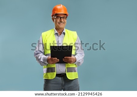 Construction site engineer with a reflective vest isolated over blue background Royalty-Free Stock Photo #2129945426
