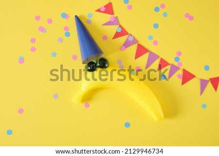 1 april date. April Fool's Day. creative minimal concept. creative postcard with a plastic banana in a cap with eyes on a yellow background