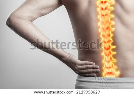 human anatomy of spinal cord signifying lower spine pain. Man with inflamed spinal cord injury pain highlighted in glowing red. Royalty-Free Stock Photo #2129958629