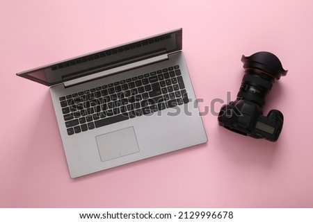 Laptop with digital camera on a pink background. Top view.