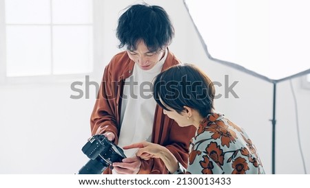Asian people watching LCD of camera in the shooting studio.