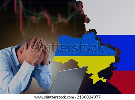 A failed investor sitting sad in front of laptop with Ukraine and Russia flag with stock market chart turn red and going down. Economic crisis because of the war concept. Royalty-Free Stock Photo #2130024077