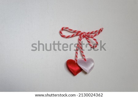 Traditional martenitsa with hearts, made from red and white yarn on a white background. Bulgarian tradition. Baba Marta Day. Symbol of the coming spring and of new life.