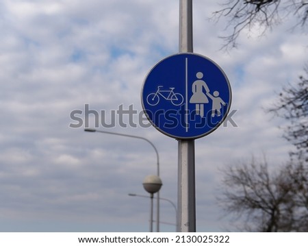 Bicycle and pedestrian lane road sign on a meatl pole post with the sky in the background
