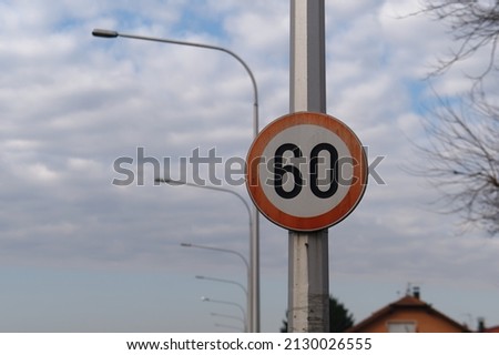 Close-up picture of a 60-speed limit road sign on a pole post with a sky in the background