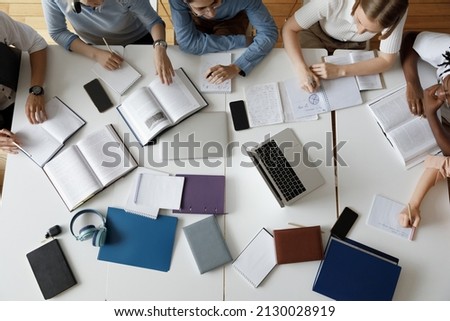 Above top view concentrated happy multiracial diverse team of young students using gadgets and books preparing for exams, working together on college project in library or campus, learning concept. Royalty-Free Stock Photo #2130028919