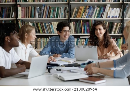 Happy group of diverse multiracial friendly students talking, discussing new school project ideas together, enjoying preparing for examinations, doing common research in library, education concept. Royalty-Free Stock Photo #2130028964
