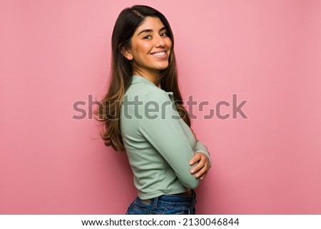Side view of an attractive hispanic woman feeling happy in front of a bright pink background Royalty-Free Stock Photo #2130046844