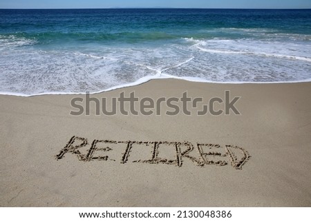 Words written in sand. The word RETIRED written in the sand on the beach with the ocean in the background. When retired you have more time to enjoy the beach and ocean. Relax you are Retired. Retired. Royalty-Free Stock Photo #2130048386