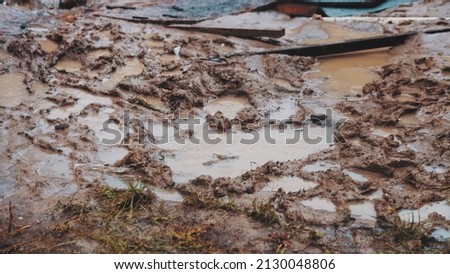 Rain Water Puddles Formed in Deep Footprints Left in Wet Muddy Ground on Messy Construction Site Royalty-Free Stock Photo #2130048806