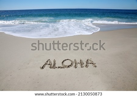 Words written in the sand on the beach. The word ALOHA written in the sand with the ocean background. Aloha is the Hawaiian word for love, affection, peace, compassion and mercy. Aloha.  Royalty-Free Stock Photo #2130050873