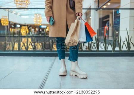 Close-up of a woman holding shopping for colorful shopping bags in a mall .A close-up shot of a young woman with colorful shopping bags while walking through a mall.  Shopping concept
