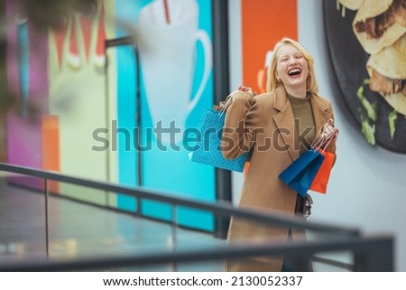 Portrait of casually dressed confident young woman walking in mall with bunch of shopping bags in hands. Black friday sales concept. Woman in shopping.