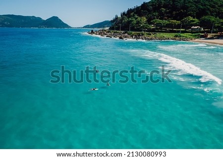 Surfers on surfboard in transparent blue ocean. Aerial view