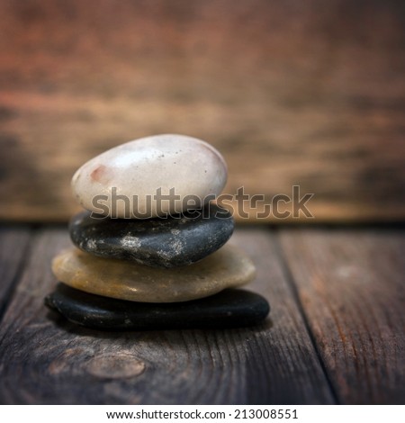 Pebbles stock on wooden background, in low light setting with vintage filter.