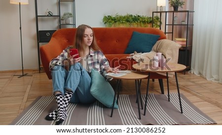 Planning family budget. Smiling happy young woman counting money cash, use mobile phone calculate domestic bills at home. Joyful girl satisfied of income and saves money for a planned vacation, gifts Royalty-Free Stock Photo #2130086252