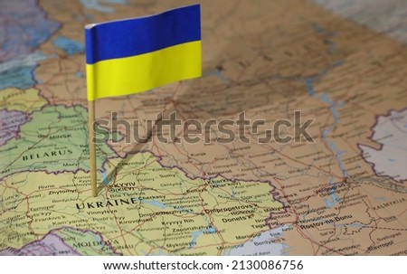 The Ukrainian flag stuck in the center of the country. Neighbouring Russia and Belarus are prominent. Atlas or world map showing location of the country of Ukraine.  Royalty-Free Stock Photo #2130086756
