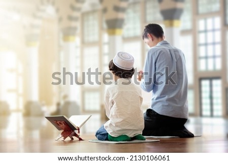 Ramadan Kareem greeting. Father and son in mosque. Muslim family praying. Man and child read Quran and pray. End of fasting. Hari Raya day. Eid al-Fitr celebration. Breaking of holy fast day.  Royalty-Free Stock Photo #2130106061