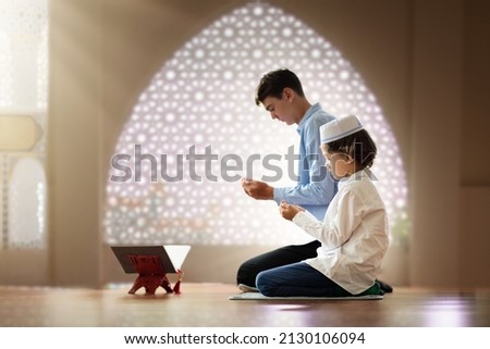 Ramadan Kareem greeting. Father and son in mosque. Muslim family praying. Man and child read Quran and pray. End of fasting. Hari Raya day. Eid al-Fitr celebration. Breaking of holy fast day.  Royalty-Free Stock Photo #2130106094