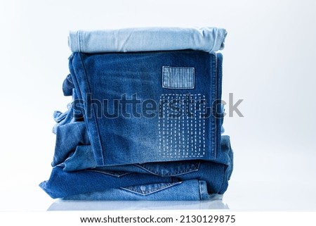 stack of blue jeans on a white background in shop.