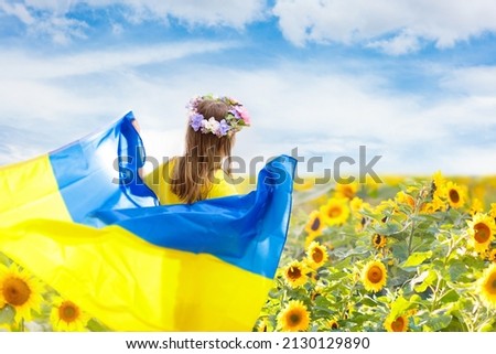 Pray for Ukraine. Child with Ukrainian flag in sunflower field. Little girl waving national flag praying for peace. Happy kid celebrating Independence Day. Royalty-Free Stock Photo #2130129890