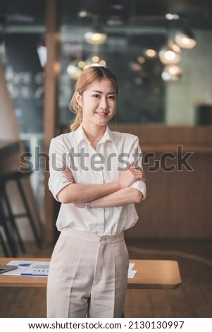 Cheerful business woman standing at office desk