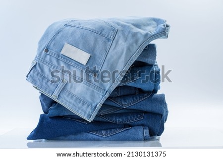 Jeans trousers stack on white background in supermarket and store. business jeans concept. Royalty-Free Stock Photo #2130131375