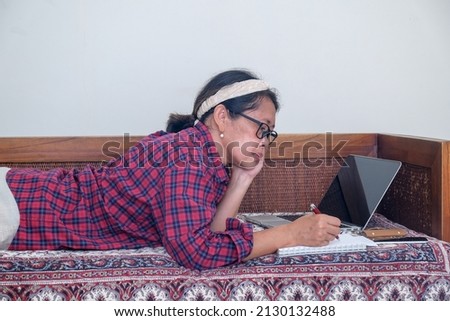Woman lying down on sofa doing her work on her laptop from home