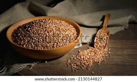 Organic buckwheat groats in a wooden bowl with a spoon on a linen napkin on a wooden table. Banner. Rustic style. Healthy nutrition concept. Buckwheat contains a large amount of vitamins and minerals.