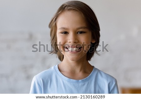 Head shot portrait front face view of handsome 9s boy having wide toothy smile looking at camera standing alone indoor. Generation Z, pre-adolescence, dental clinic services for little clients concept Royalty-Free Stock Photo #2130160289