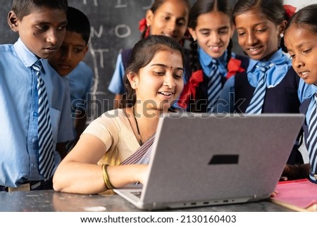 Young indian teacher teaching on laptop with school uniform students at classroom - concept of development, technology and digital education Royalty-Free Stock Photo #2130160403