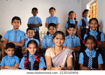 Happy smiling Kid with teacher prepared for class group photo or picture at classroom by looking at camera - concept of last day of school, childhood memories and happiness