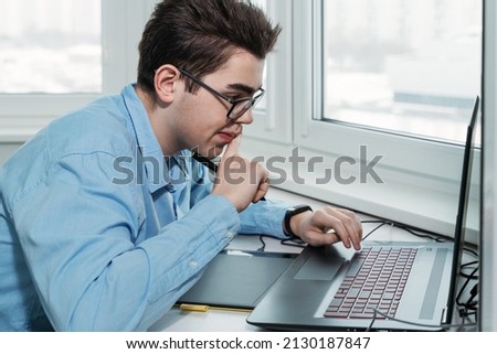 young male designer in glasses working on a professional graphics tablet with a pen