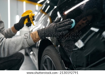 Experienced service station worker removing contaminants from automobile surface Royalty-Free Stock Photo #2130192791