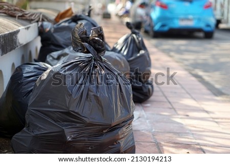 Pile of black plastic bags that contains garbage inside on the floor. Waiting for the rubbish keeper officers to take them away. Concept : Waste management. Collected for disposal.                     Royalty-Free Stock Photo #2130194213