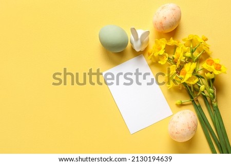 Composition with blank card, beautiful narcissus flowers and Easter eggs on color background
