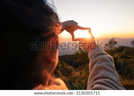 New year planning and vision concept, Close up of woman hands making frame gesture with sunset, Female capturing the sunrise. copy space. Royalty-Free Stock Photo #2130205715
