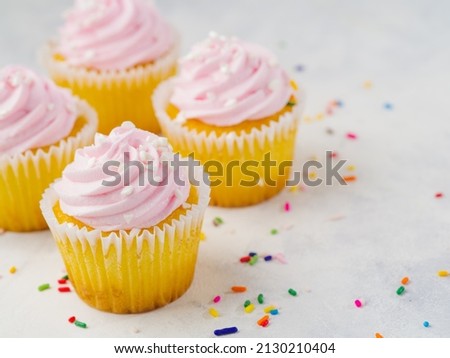 Cupcakes with pink cream isolated on white background with colorful confetti. There is an empty space to insert. Confectionery, recipes for home and restaurant cuisine, culinary blog, recipe book.