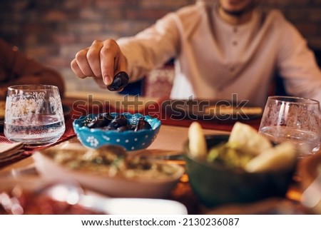 Close-up of Middle Eastern man eating date during Ramadan meal at home.  Royalty-Free Stock Photo #2130236087