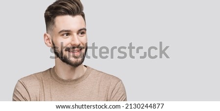 Handsome smiling young man looking up, isolated on gray background closeup portrait