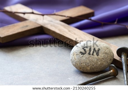 Stone with word sin, nails and wooden cross on violet fabric. Christ crucifixion for sins of people concept Royalty-Free Stock Photo #2130260255