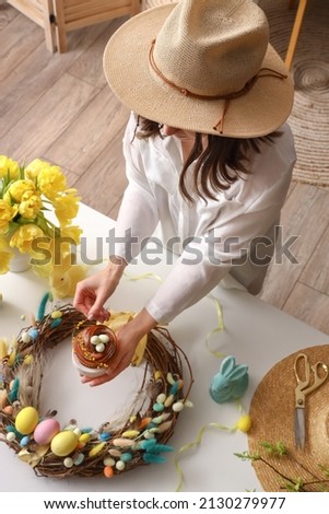 Woman holding cake on table with Easter wreath