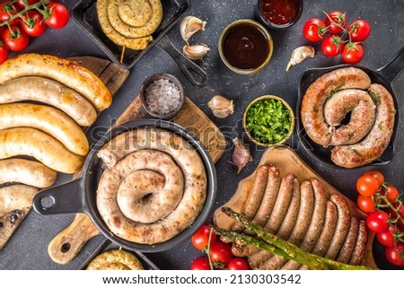 Assortment of different fried sausages. Set with various meat Bavarian, Frankfurt, German grilled sausages, Oktoberfest or summer BBQ party concept, bkack concrete background copy space top view Royalty-Free Stock Photo #2130303542