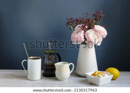 Persian pink buttercup with the wooden brown tray on a white table opposite the dark blue wall. Time to drink tea. Ceramic teapot and two porcelain cups. Copy space