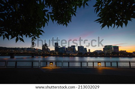 Downtown Portland cityscape during beautiful late sunset framed with tree leaves
